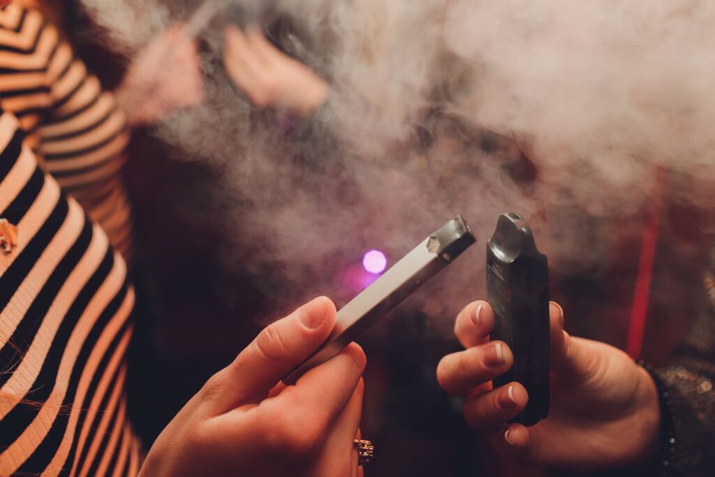 2 people sharing a juul and vape at a party