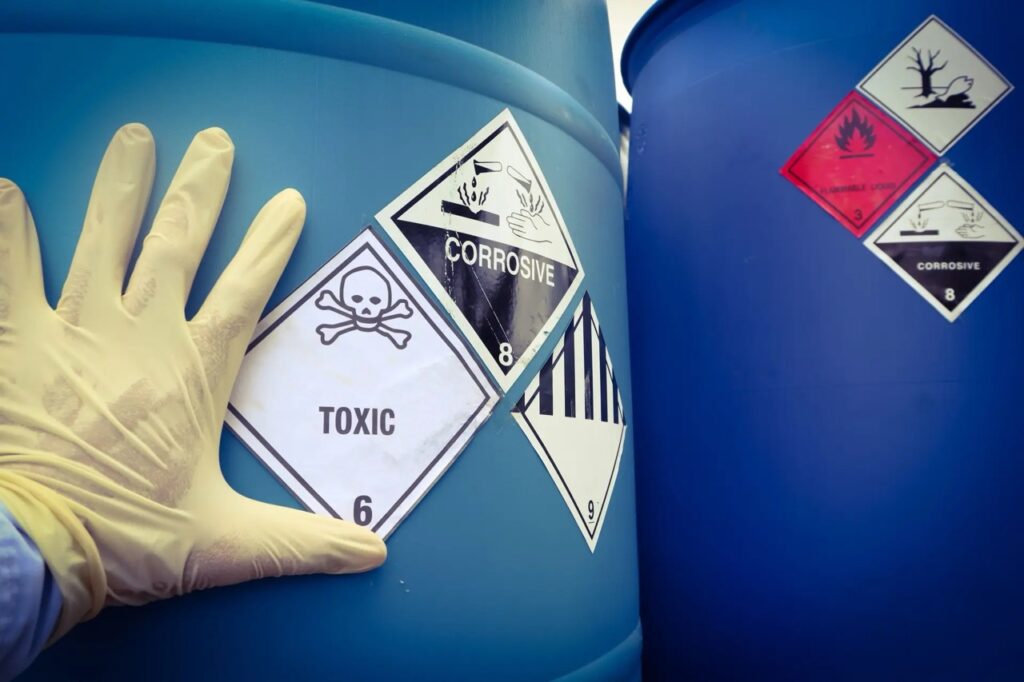mans hand on barrel of toxic waste