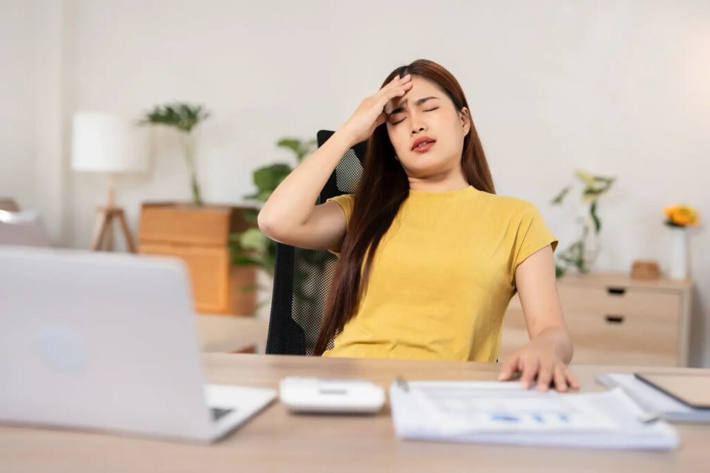woman holding head at desk
